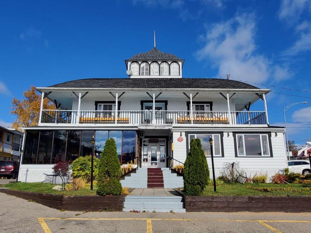 a large white house with a tower on top at Hotel - Motel Georges in Tadoussac