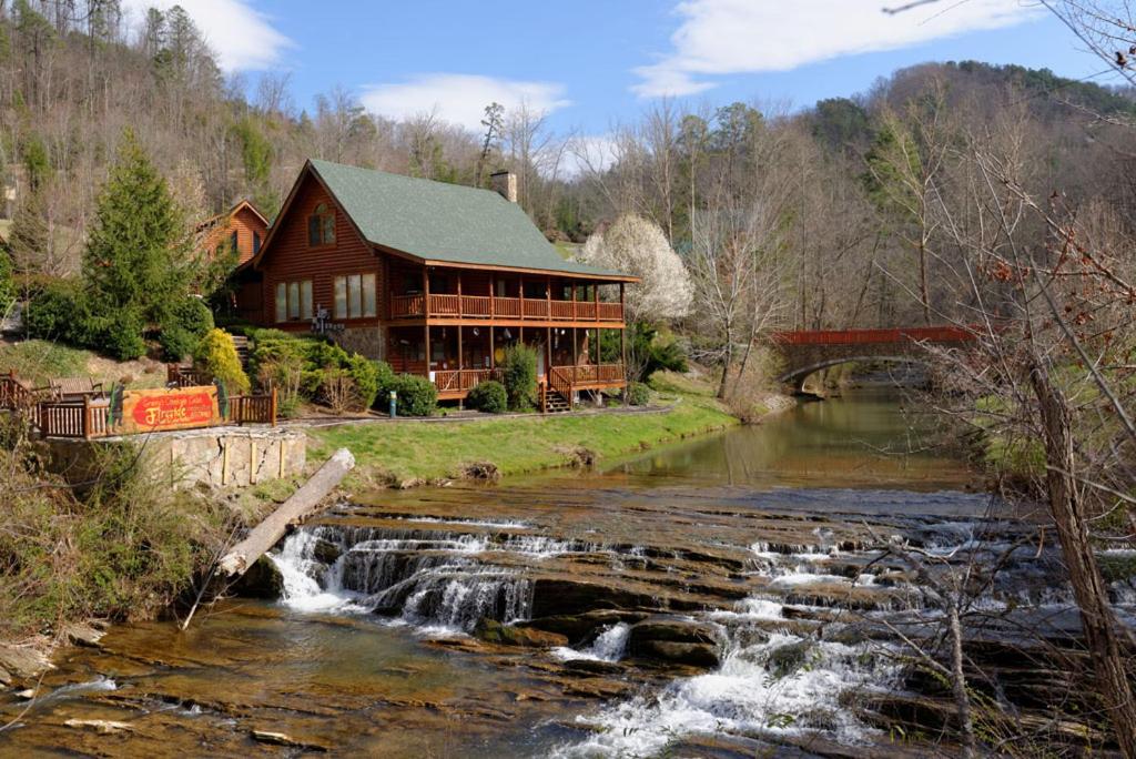 a log cabin next to a river with a waterfall at Creekside Lodge in Sevierville