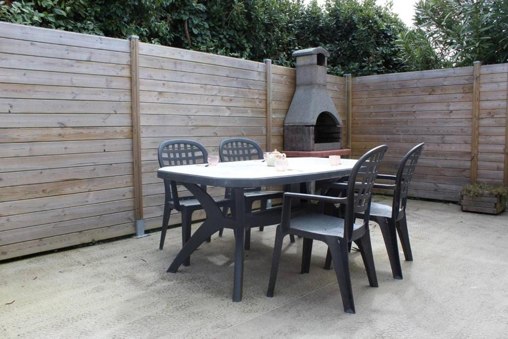 a table with four chairs and an outdoor oven at Maison 3 pièces 4 couchages Dolus d'Oléron DDO000-176 in Dolus d'Oléron