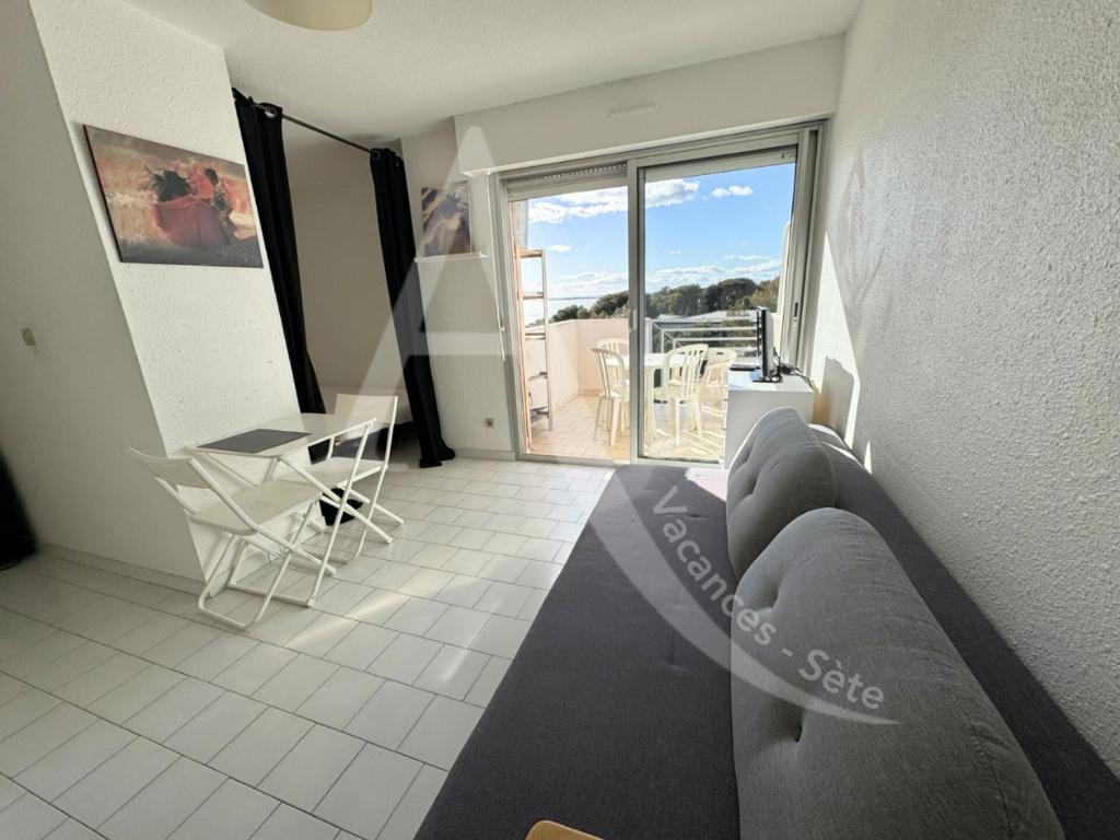 d'un salon avec un canapé et une table ainsi que d'un balcon. dans l'établissement Studio avec balcon et parking a 2 pas des plages, à Sète