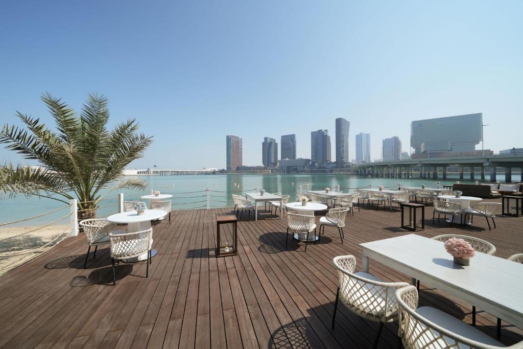 a deck with tables and chairs and a view of the water at Le Meridien Abu Dhabi in Abu Dhabi