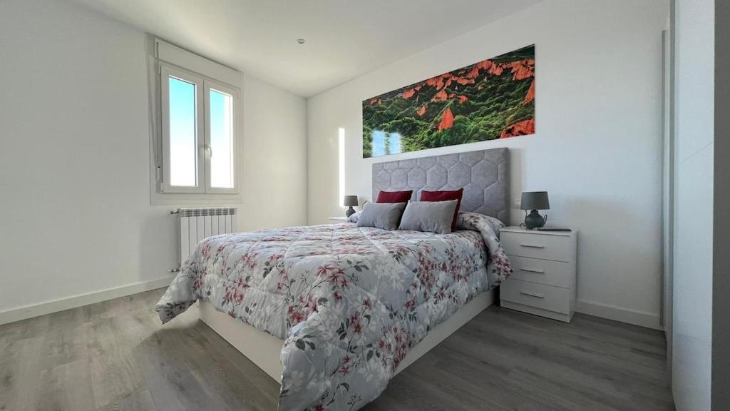 a white bedroom with a bed and a painting on the wall at Apartamento nuevo casco antiguo in Ponferrada