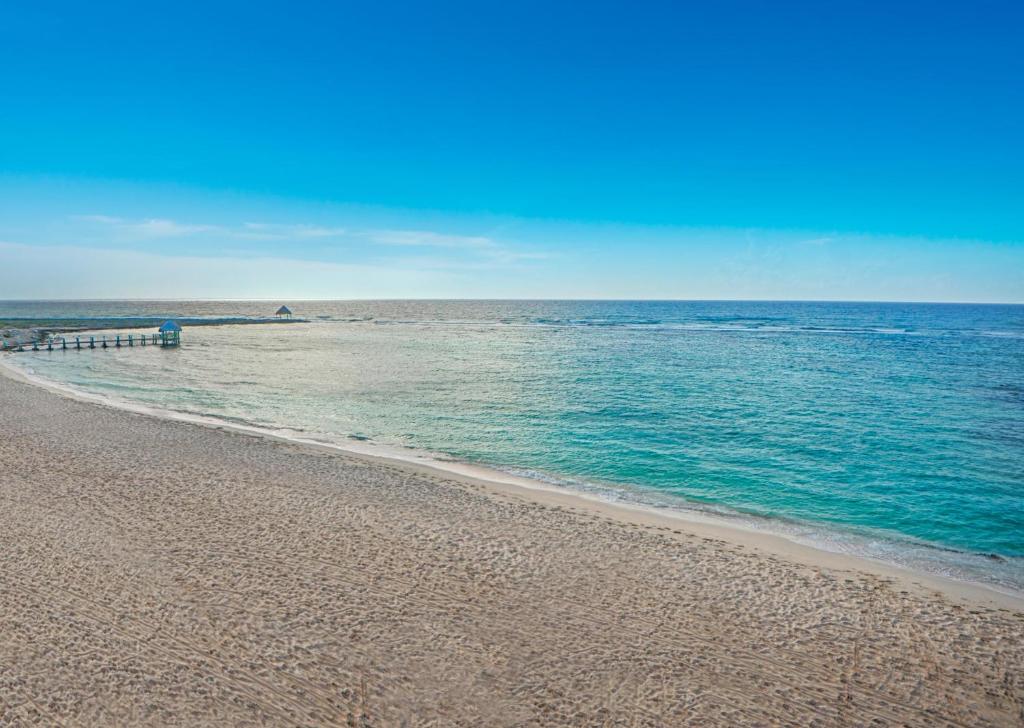 a sandy beach with a pier in the water at Grand Oasis Tulum Riviera - All Inclusive in Akumal