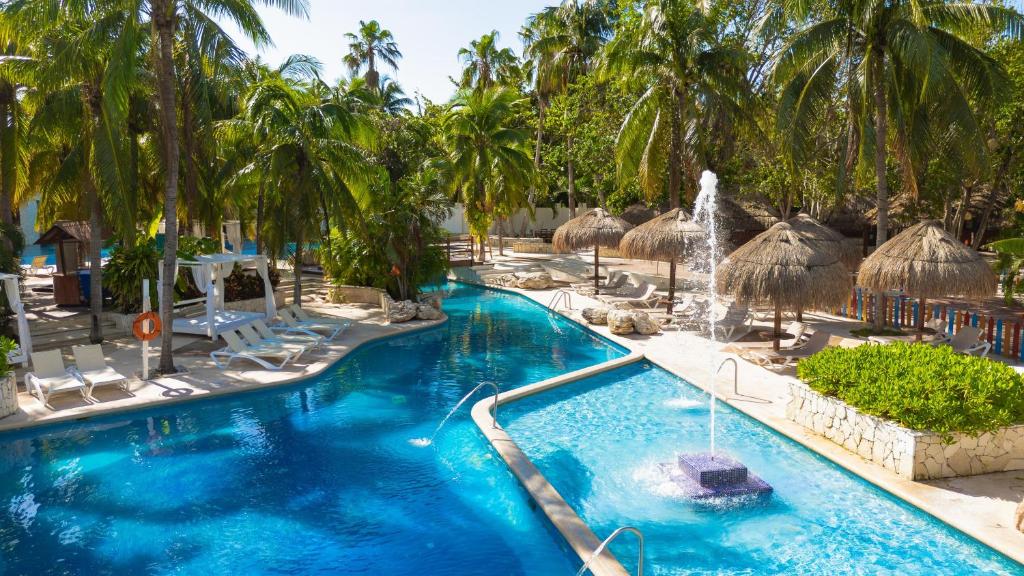 a swimming pool with palm trees and a fountain at Grand Oasis Tulum Riviera - All Inclusive in Akumal