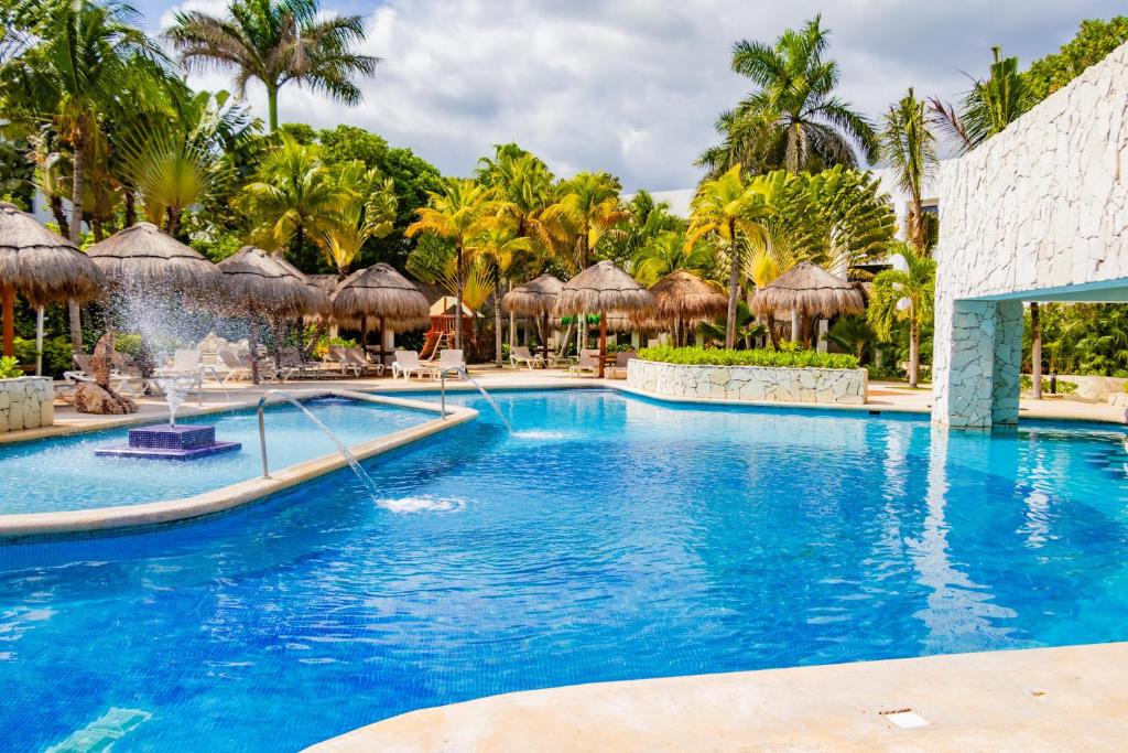 a pool at a resort with palm trees and umbrellas at Grand Oasis Tulum Riviera - All Inclusive in Akumal