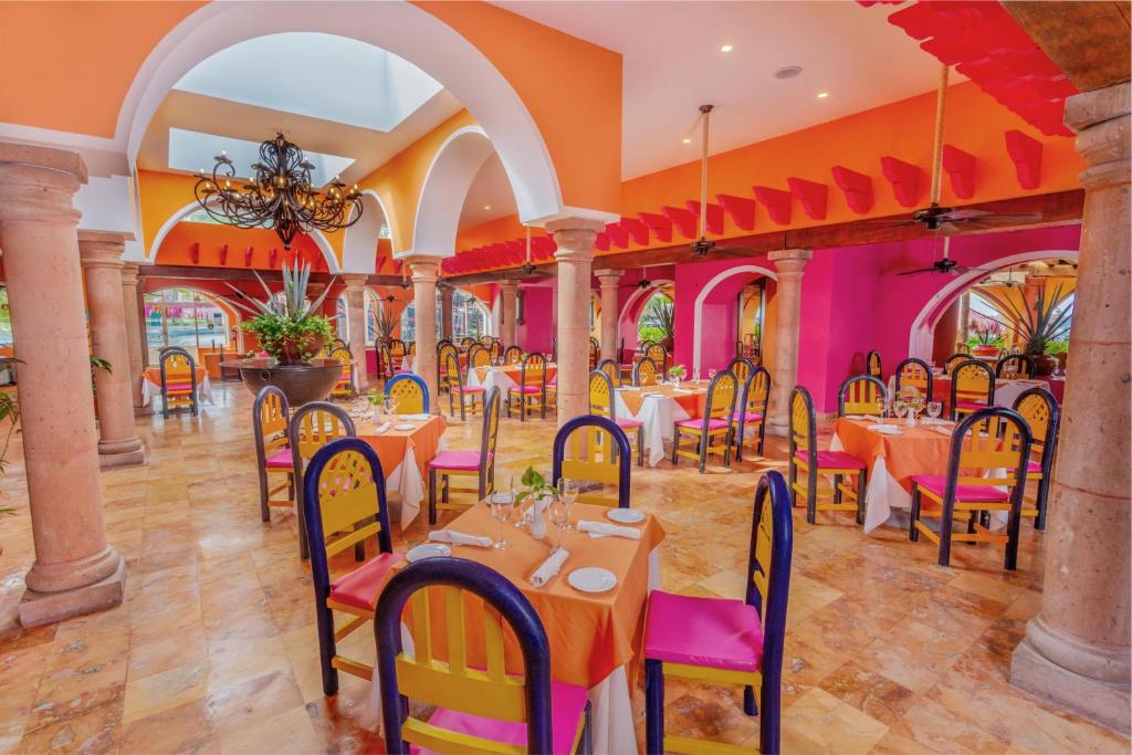 Colorful dining room with pink and orange walls, arched ceilings, and set tables.