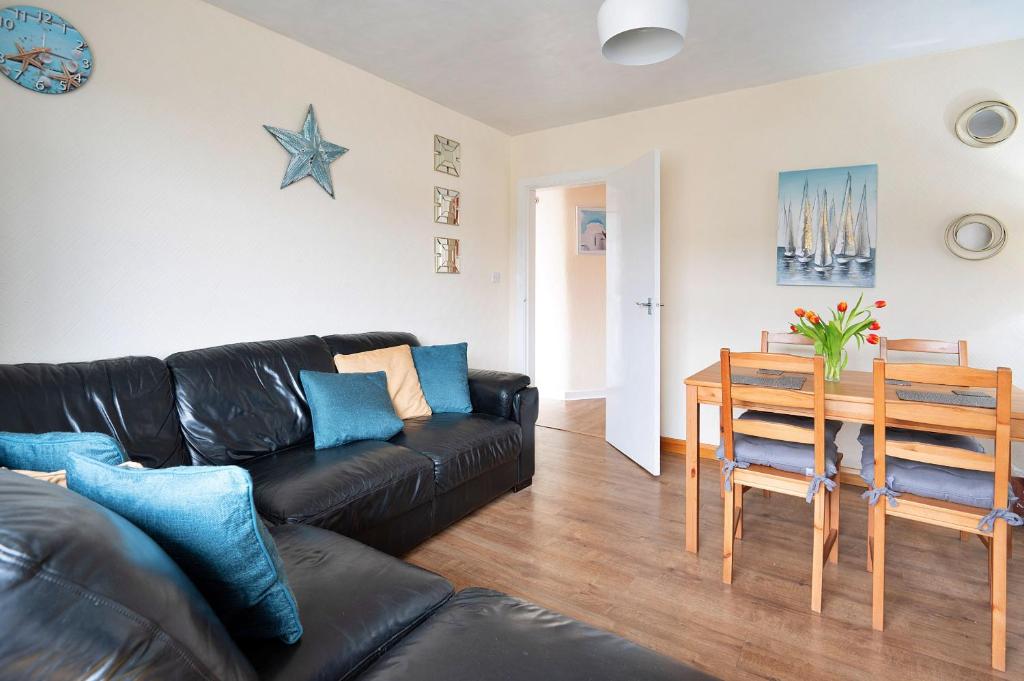 a living room with a black leather couch and a table at Finest Retreats - Llys Llewellyn in Kinmel Bay