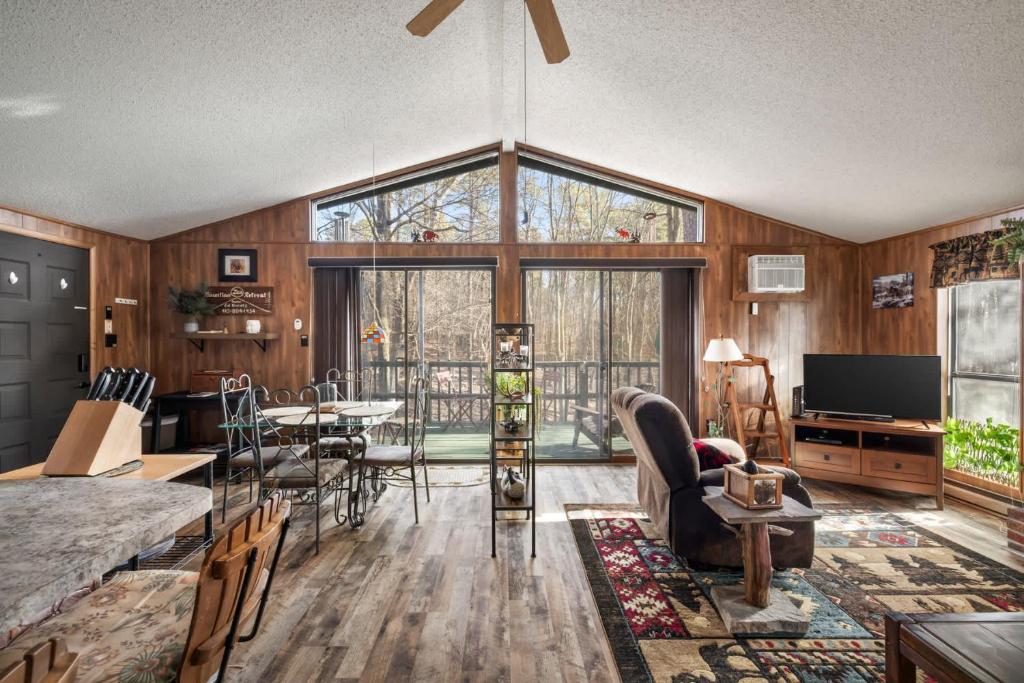 a living room with wooden walls and a large window at Zen Vibe w Fireplace Grill Deck & Screened Porch in Hedgesville