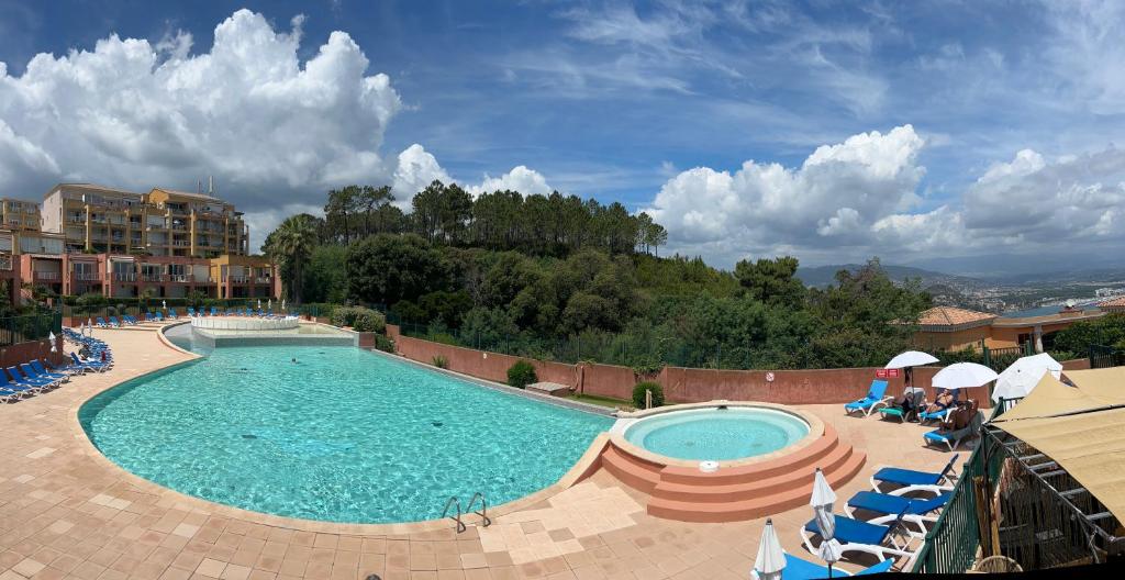 une grande piscine avec des chaises et des parasols dans un complexe dans l'établissement Climatisé, piscine, proches des plages, à Théoule-sur-Mer
