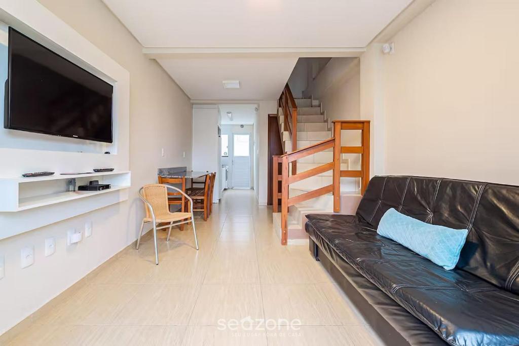 ein Wohnzimmer mit einer schwarzen Ledercouch und einem Tisch in der Unterkunft Casa 2Q c churrasq a 600m do mar RVL118 in Canto Grande