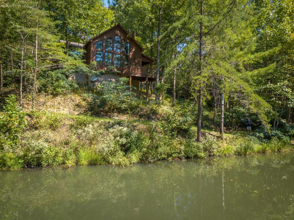 a house in the woods next to a body of water at Reflections in Sevierville