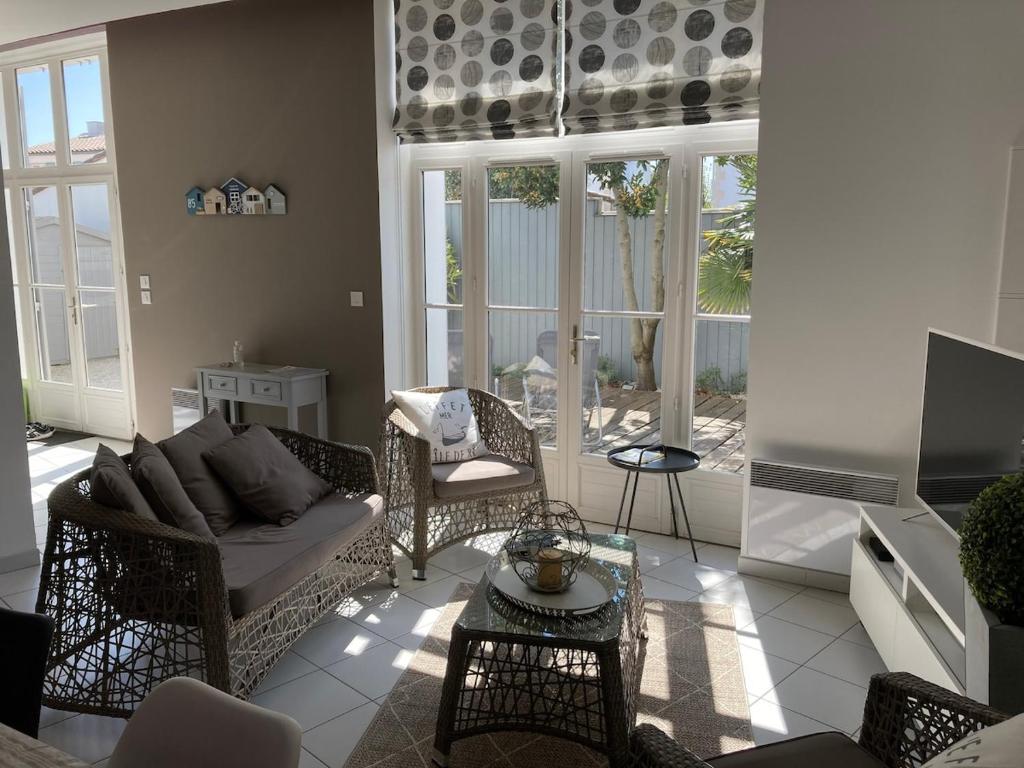 un salon avec un canapé, des chaises et une télévision dans l'établissement Charme et confort à St Martin de Ré avec terrasse & parking, à Saint-Martin-de-Ré