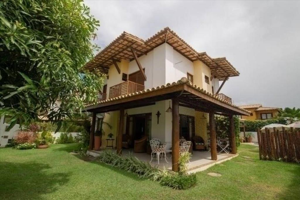 a small house with a balcony and a yard at Casa de Praia em Guarajuba-Genipabu-BA in Guarajuba