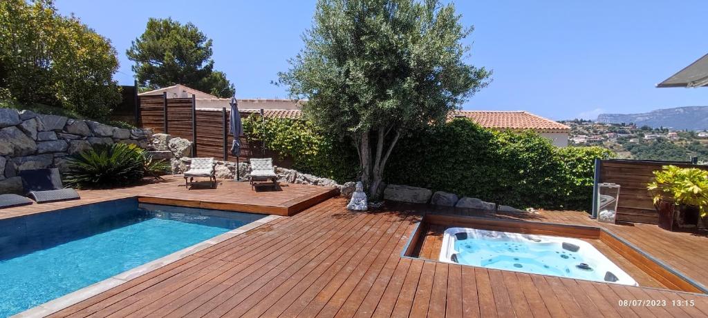 une cour arrière avec une piscine et une terrasse en bois dans l'établissement VILLA MODERNE PISCINE JACUZZi, à Nice