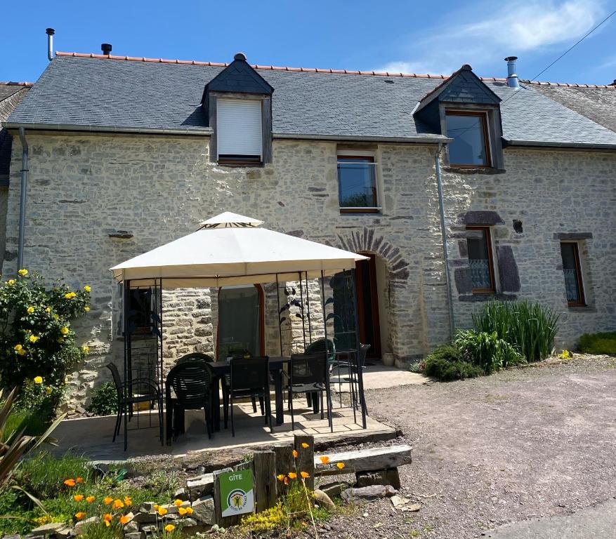 une maison avec une table et des chaises sous un parasol dans l'établissement Gîte La Longère, à Laillé