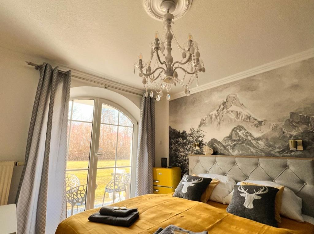 a bedroom with a large bed and a chandelier at Bavaria Mountain Lodge Chalet DESIGN Ferienwohnung SKI Arber Osser Terrasse Sauna in Villa bis 5 Pers in Hohenwarth