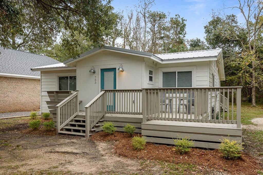 a small white house with a large deck at Cottage in the Village in Dauphin Island