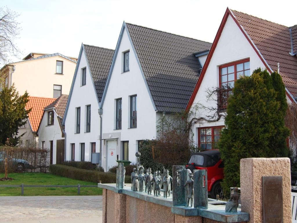 eine Gruppe weißer Häuser mit einer Statue vor ihnen in der Unterkunft Ferienwohnung in der Altstadt Warnemünde in Warnemünde