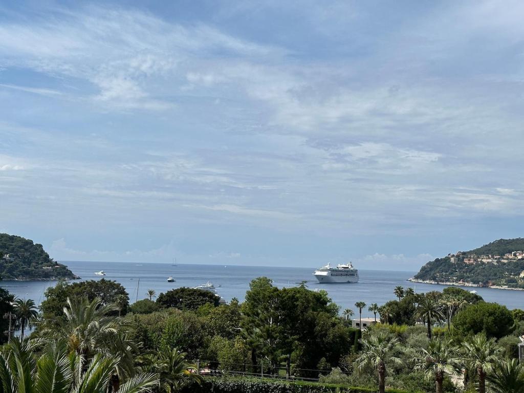 un navire de croisière dans l'eau avec des arbres et une plage dans l'établissement Apartment Nice-Monaco, à Villefranche-sur-Mer