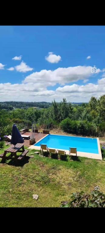 a large swimming pool with benches in a field at La Cumbre in Sierra de los Padres