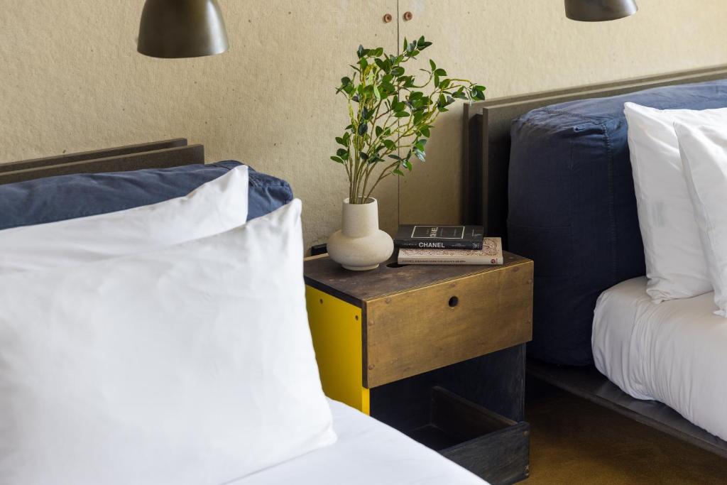 a bedroom with two beds and a table with a plant on it at STILE Downtown Los Angeles by Kasa in Los Angeles