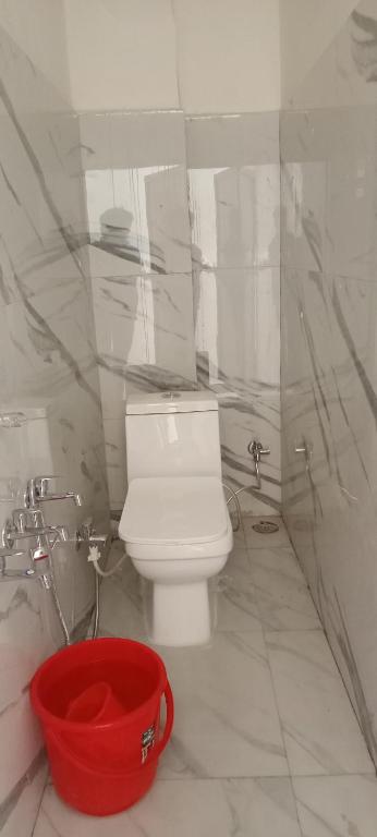 a bathroom with a white toilet and a red bucket at Malik kripa Home stay in Prayagraj