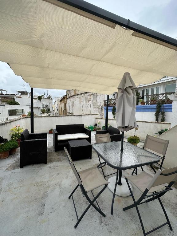 patio ze stołem, krzesłami i parasolem w obiekcie Gabriele-Apartment w mieście Gallipoli