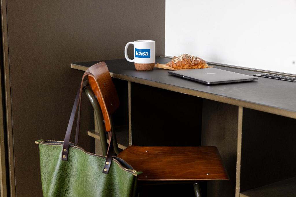 a green bag sitting next to a desk with a laptop at STILE Downtown Los Angeles by Kasa in Los Angeles
