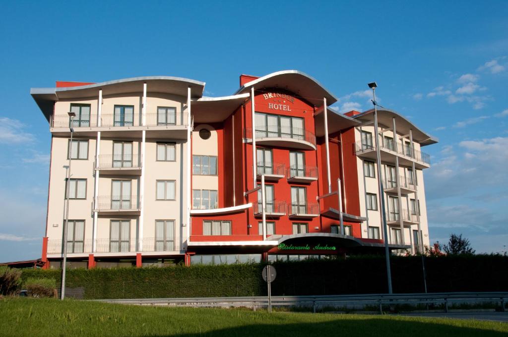 un grand bâtiment rouge et blanc à côté d'une rue dans l'établissement Hotel Brindor, à Poirino