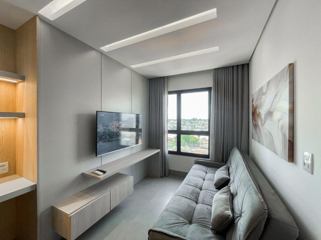 a living room with a couch and a tv at Lindo Flat Planejado com Vista Para Cidade in Campo Grande