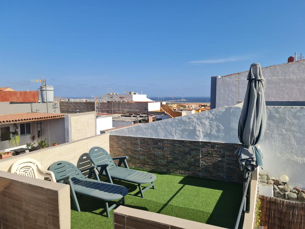 een patio met 2 stoelen en een parasol op een dak bij 3Brooms APARTMENT 90 M2 TERASSE 18M2 AirCondit in Vecindario