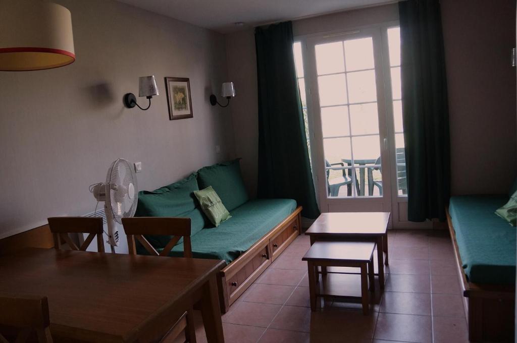 un salon avec un canapé vert et une table dans l'établissement La résidence du Lac - maeva Home - Appartement 2 pièces 5 personnes - Sélection MAE-4254, à Monflanquin
