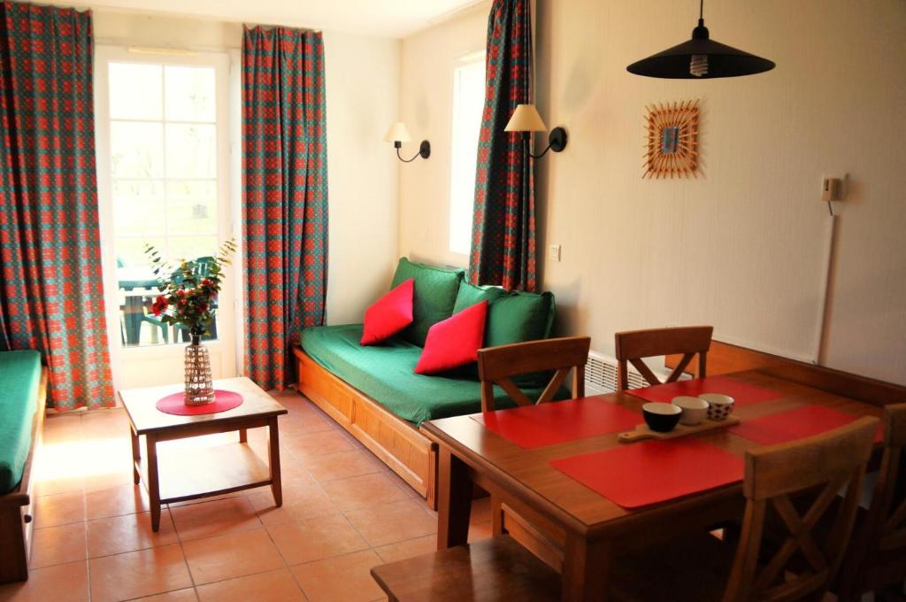 un salon avec un canapé vert avec des coussins rouges dans l'établissement La résidence du Lac - maeva Home - Appartement 2 pièces 5 personnes - Sélection MAE-2491, à Monflanquin