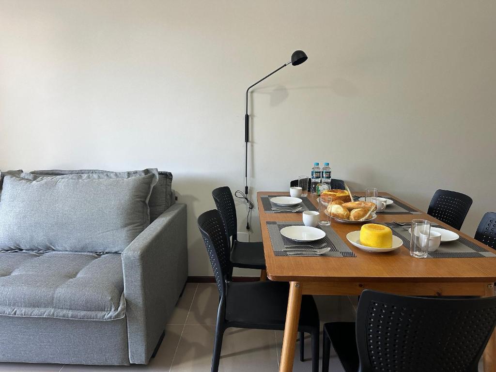 una sala de estar con una mesa y un sofá en Ap a alguns passos da praia do Bosque | ROGR104, en Rio das Ostras