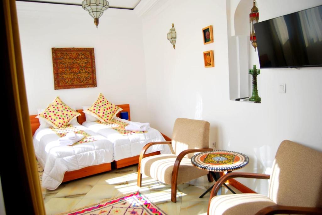 1 Schlafzimmer mit 2 Betten, einem Tisch und Stühlen in der Unterkunft Dar terrae plus in Chefchaouen