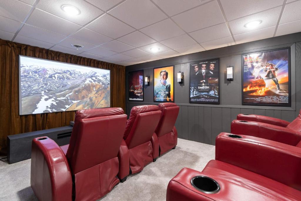 a movie room with red chairs and a large screen at Luxury Designer Home Theatre Games & BBQ Grill in Millard