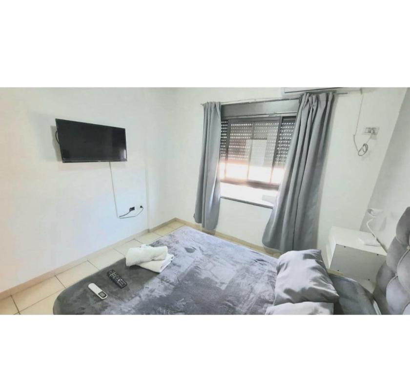 a bedroom with a bed and a window with a television at Departamento sobre Boulevard con cochera in Santa Fe