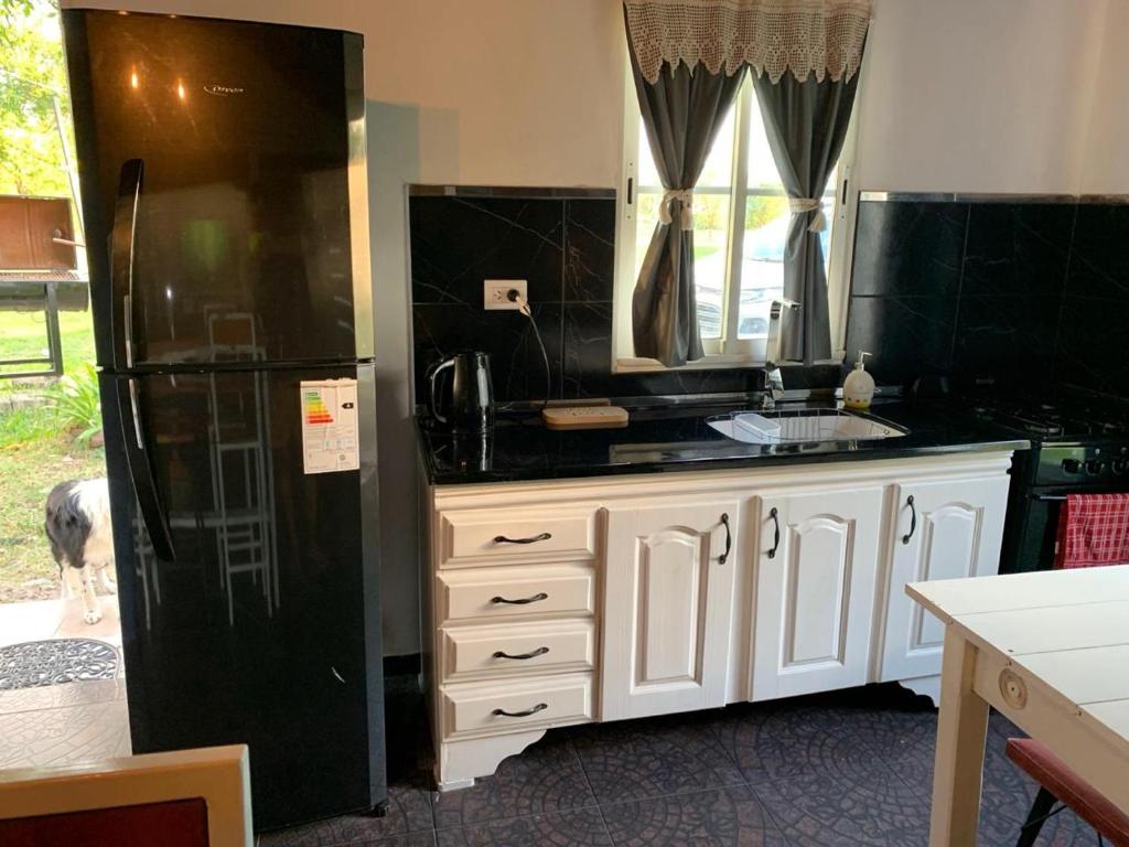 a kitchen with a black refrigerator and white cabinets at Luz del Norte in Federación