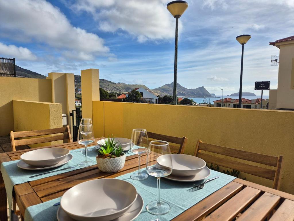 einen Tisch mit Tellern und Weingläsern auf dem Balkon in der Unterkunft Cantinho do Porto Santo in Porto Santo