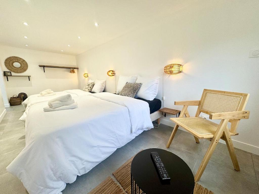 a bedroom with a large white bed and a chair at TheLittleHouse - Maison- Jardin in Calais