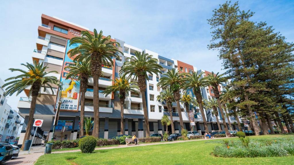 モハメディアにあるCharmant appartement joyau du parc 200m plageのヤシの木が前に生えている大きな建物