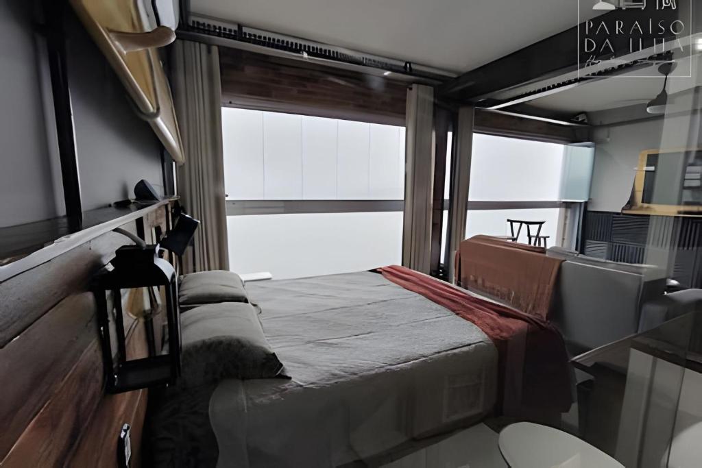 a large bed in a room with a window at Apartamento Chalé da Ilha - Ar Cond e Super VISTA in São Vicente