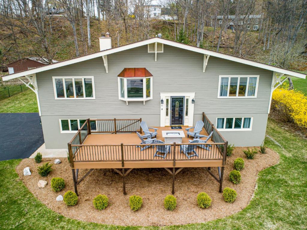 a house with a deck with a table and chairs at Up North Escape - Modern Home with Private Beach in Traverse City