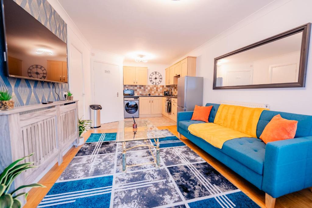 a living room with a blue couch and a kitchen at Bright & Elegant House Near City Centre and Stadium in Cardiff