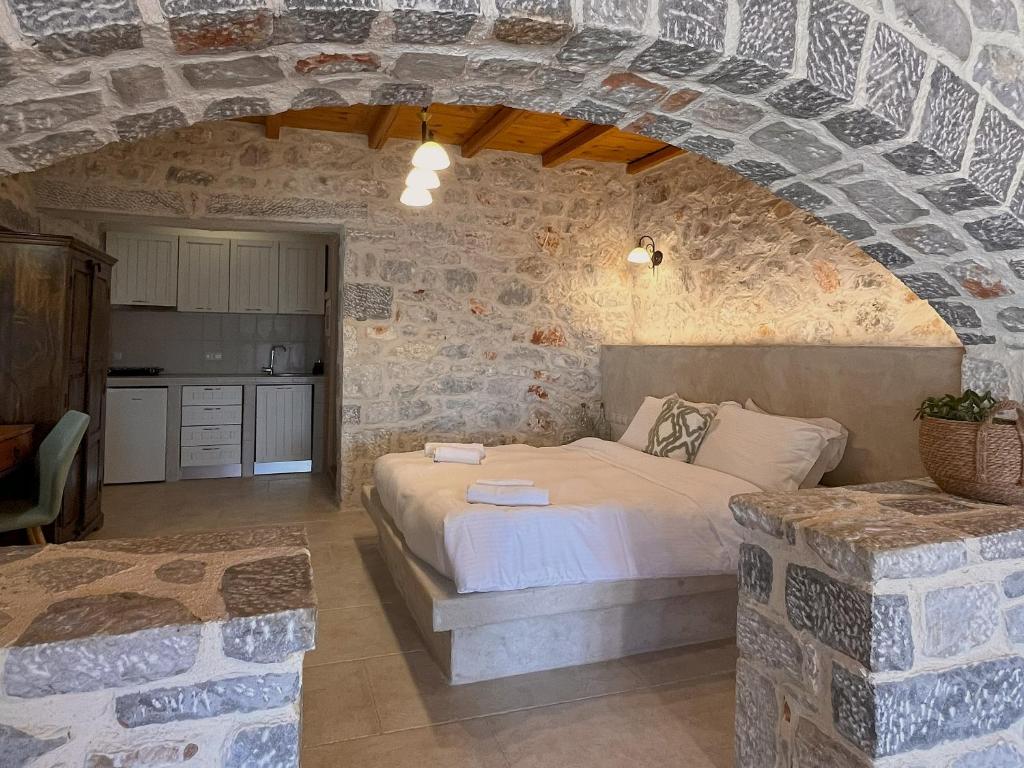ein Schlafzimmer mit einem Bett in einer Steinwand in der Unterkunft Achelatis Traditional Guest Houses in Areopoli