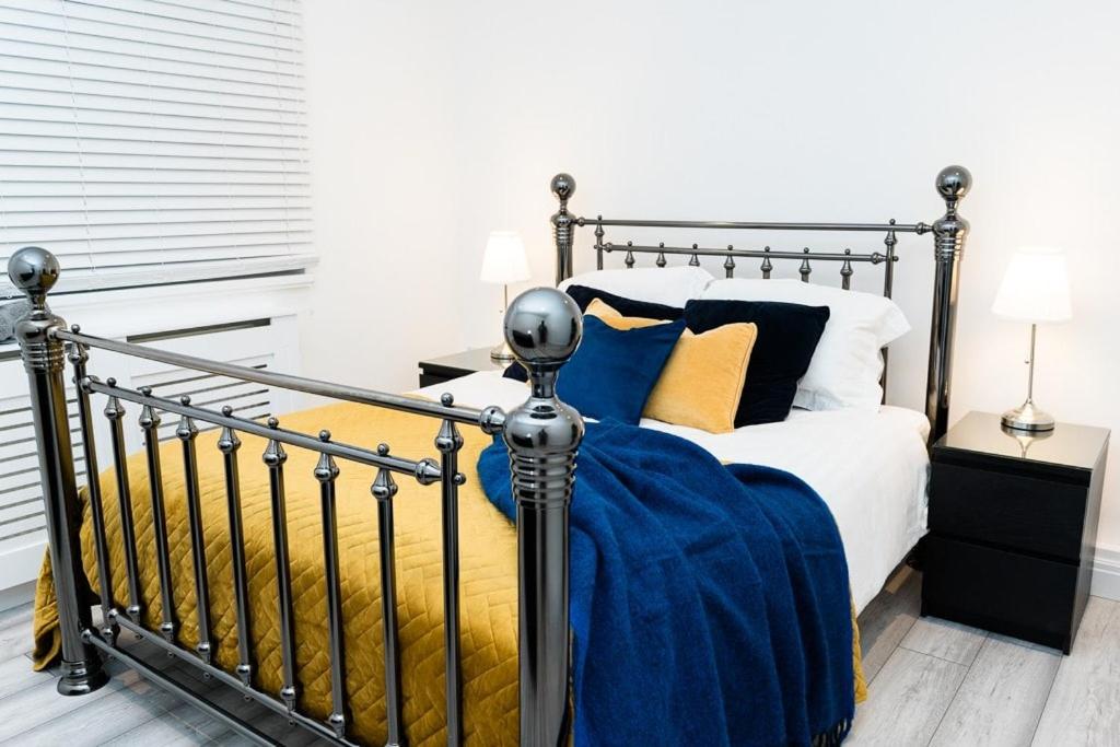a bedroom with a bed with blue and yellow pillows at Angel Apartments - Affordable Stylish Luxury Stay near Station - Victoria 20mins in Mitcham Junction