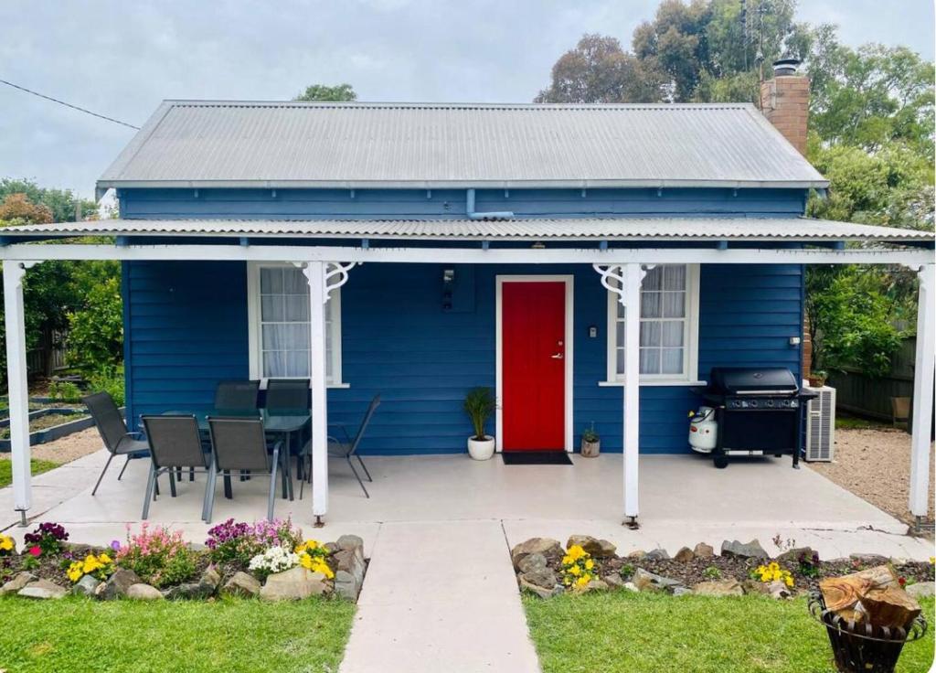 una casa blu con una porta rossa e una griglia di The Blue Cottage a Orbost