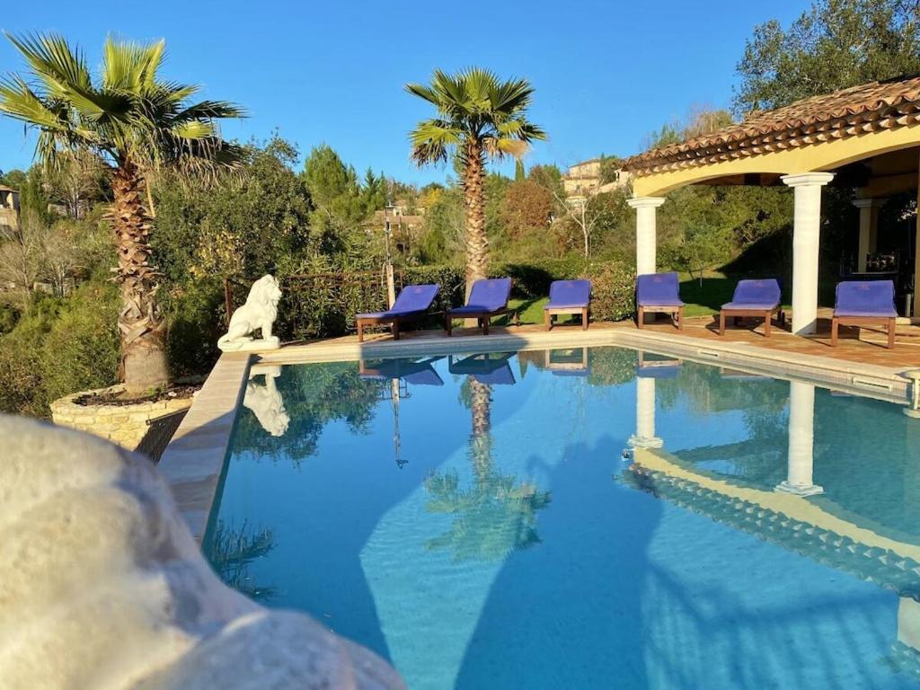 - une piscine avec des chaises violettes et des palmiers dans l'établissement Soleil des Adrets Comfortable holiday residence, à Montauroux