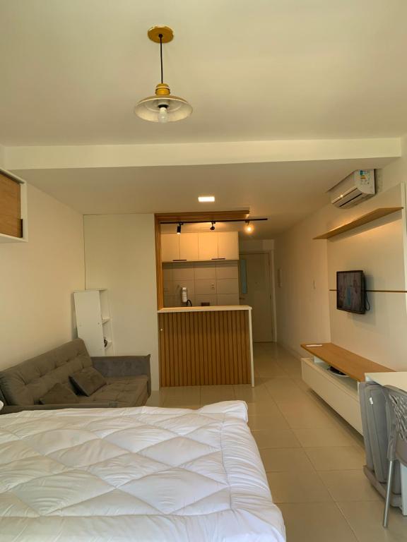 Un dormitorio con una cama blanca y un sofá. en Loft em Armação, Centro de convenções, en Salvador