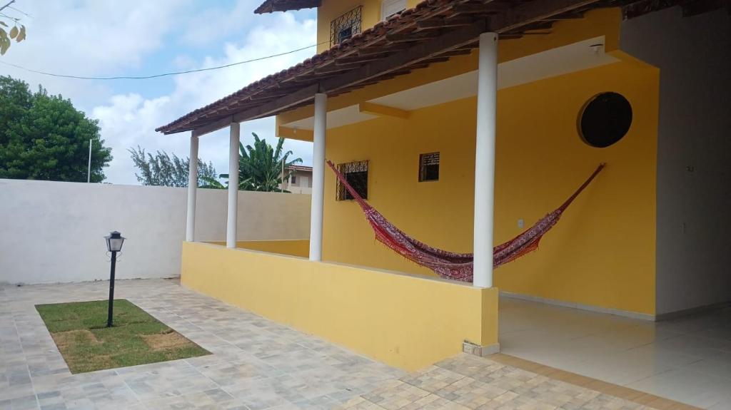 a yellow house with a hammock on the side of it at Recanto do Ze Bonito in Conde